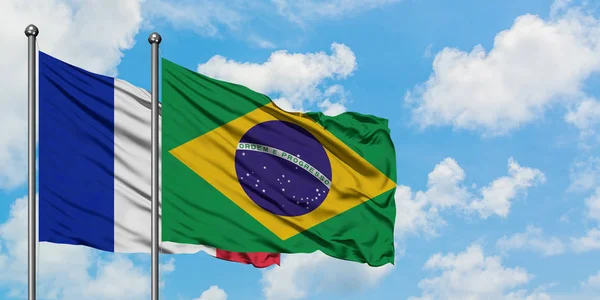 Bandera de Francia y Brasil ondeando en el viento contra el cielo azul nublado blanco juntos. Concepto diplomático, relaciones internacionales . —  Fotos de Stock