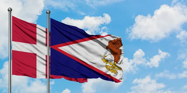 Bandera de Dinamarca y Samoa Americana ondeando en el viento contra el cielo azul nublado blanco juntos. Concepto diplomático, relaciones internacionales . — Foto de Stock