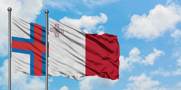 Bandera de las Islas Feroe y Malta ondeando en el viento contra el cielo azul nublado blanco juntos. Concepto diplomático, relaciones internacionales . — Foto de Stock