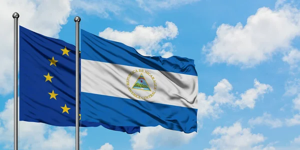Europäische Union und Nicaragua-Flagge wehen gemeinsam im Wind vor dem wolkenverhangenen blauen Himmel. Diplomatie-Konzept, internationale Beziehungen. — Stockfoto
