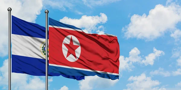 El Salvador ve Kuzey Kore bayrağı birlikte beyaz bulutlu mavi gökyüzüne karşı rüzgarda sallayarak. Diplomasi kavramı, uluslararası ilişkiler. — Stok fotoğraf