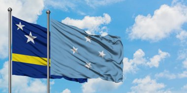 Curacao ve Mikronezya bayrağı birlikte beyaz bulutlu mavi gökyüzüne karşı rüzgarda sallayarak. Diplomasi kavramı, uluslararası ilişkiler.