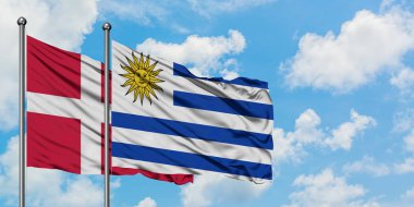 Danimarka ve Uruguay bayrağı birlikte beyaz bulutlu mavi gökyüzüne karşı rüzgarda sallayarak. Diplomasi kavramı, uluslararası ilişkiler.