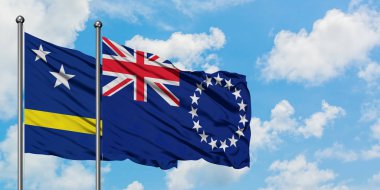 Curacao ve Cook Adaları bayrak birlikte beyaz bulutlu mavi gökyüzüne karşı rüzgarda sallayarak. Diplomasi kavramı, uluslararası ilişkiler.