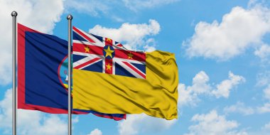 Guam ve Niue bayrağı birlikte beyaz bulutlu mavi gökyüzüne karşı rüzgarda sallayarak. Diplomasi kavramı, uluslararası ilişkiler.