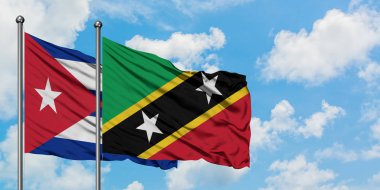 Küba ve Saint Kitts ve Nevis bayrağı birlikte beyaz bulutlu mavi gökyüzüne karşı rüzgarda sallayarak. Diplomasi kavramı, uluslararası ilişkiler.