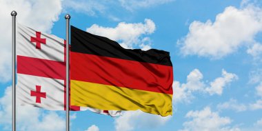 Gürcistan ve Almanya bayrağı birlikte beyaz bulutlu mavi gökyüzüne karşı rüzgarsal sallayarak. Diplomasi kavramı, uluslararası ilişkiler.