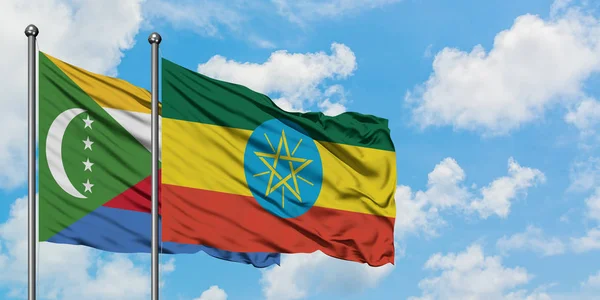 Bandera de las Comoras y Etiopía ondeando en el viento contra el cielo azul nublado blanco juntos. Concepto diplomático, relaciones internacionales . — Foto de Stock