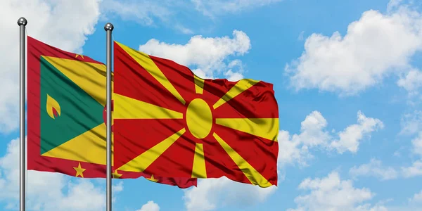 Granada e Macedónia acenando ao vento contra o céu azul nublado branco juntos. Conceito de diplomacia, relações internacionais . — Fotografia de Stock
