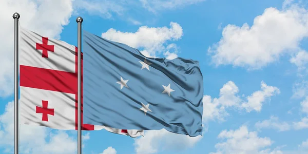 Bandera de Georgia y Micronesia ondeando en el viento contra el cielo azul nublado blanco juntos. Concepto diplomático, relaciones internacionales . — Foto de Stock