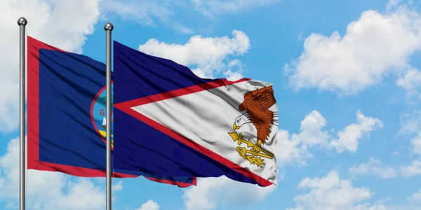 Guam e a bandeira americana de Samoa agitando no vento contra o céu azul nublado branco juntos. Conceito de diplomacia, relações internacionais . — Fotografia de Stock