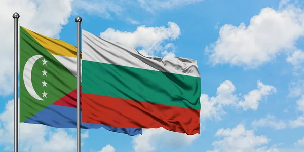 Bandera de las Comoras y Bulgaria ondeando en el viento contra el cielo azul nublado blanco juntos. Concepto diplomático, relaciones internacionales . — Foto de Stock
