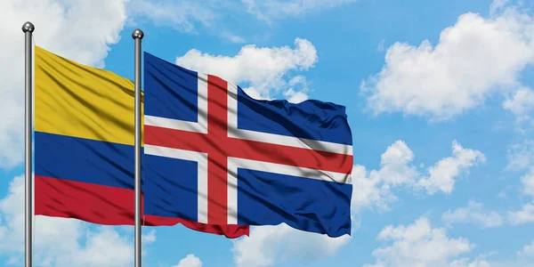 Bandera de Colombia e Islandia ondeando en el viento contra el cielo azul nublado blanco juntos. Concepto diplomático, relaciones internacionales . — Foto de Stock