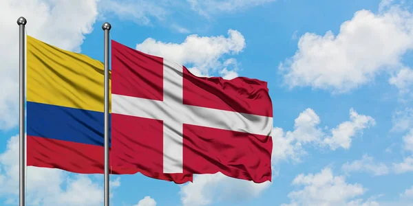 Colombia en Denemarken vlag zwaaiende in de wind tegen witte bewolkte blauwe hemel samen. Diplomatie concept, internationale betrekkingen. — Stockfoto