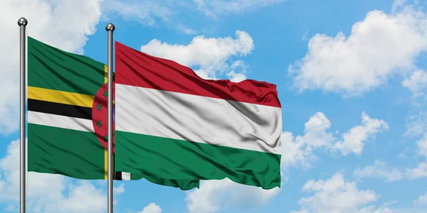 Bandera de Dominica y Hungría ondeando en el viento contra el cielo azul nublado blanco juntos. Concepto diplomático, relaciones internacionales . — Foto de Stock