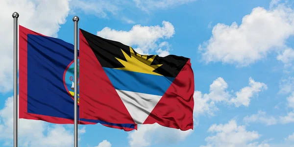 Guam ve Antigua ve Barbuda bayrağı birlikte beyaz bulutlu mavi gökyüzüne karşı rüzgarda sallayarak. Diplomasi kavramı, uluslararası ilişkiler. — Stok fotoğraf
