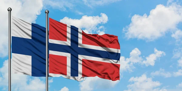 Finnland und Norwegen wehen gemeinsam im Wind vor dem wolkenverhangenen blauen Himmel. Diplomatie-Konzept, internationale Beziehungen. — Stockfoto