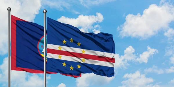 Bandera de Guam y Cabo Verde ondeando en el viento contra el cielo azul nublado blanco juntos. Concepto diplomático, relaciones internacionales . — Foto de Stock