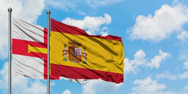 건지와 스페인 국기가 함께 하얀 흐린 푸른 하늘에 대한 바람에 흔들리고. 외교 개념, 국제 관계. — 스톡 사진