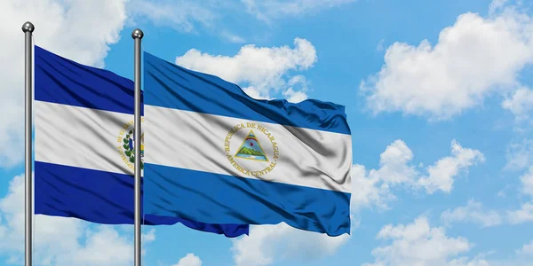Bandera de El Salvador y Nicaragua ondeando en el viento contra el cielo azul nublado blanco juntos. Concepto diplomático, relaciones internacionales . —  Fotos de Stock