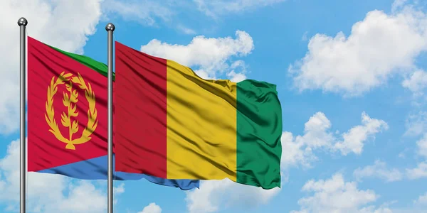 Bandera de Eritrea y Guinea ondeando en el viento contra el cielo azul nublado blanco juntos. Concepto diplomático, relaciones internacionales . — Foto de Stock