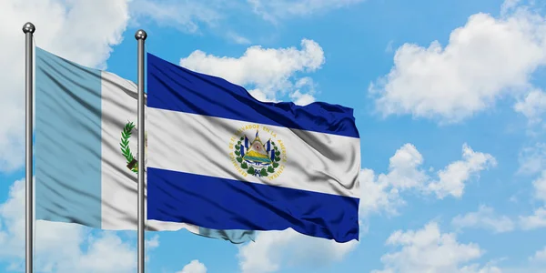 Drapeau du Guatemala et du Salvador agitant dans le vent contre le ciel bleu nuageux blanc ensemble. Concept de diplomatie, relations internationales . — Photo