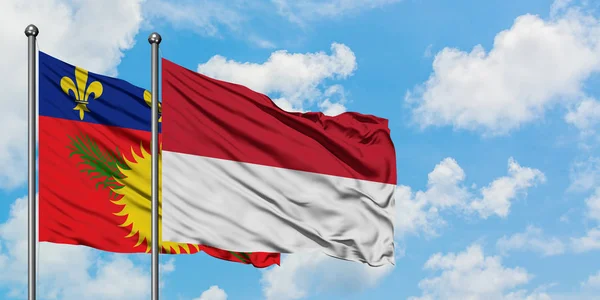 Guadalupe y la bandera de Indonesia ondeando en el viento contra el cielo azul nublado blanco juntos. Concepto diplomático, relaciones internacionales . —  Fotos de Stock