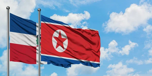 多米尼加共和国和朝鲜国旗在风中飘扬，与白云蓝天相一起。外交概念、国际关系. — 图库照片