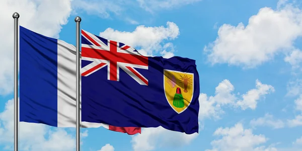 Frankrijk en Turks-en Caicoseilanden vlag zwaaien in de wind tegen witte bewolkte blauwe hemel samen. Diplomatie concept, internationale betrekkingen. — Stockfoto