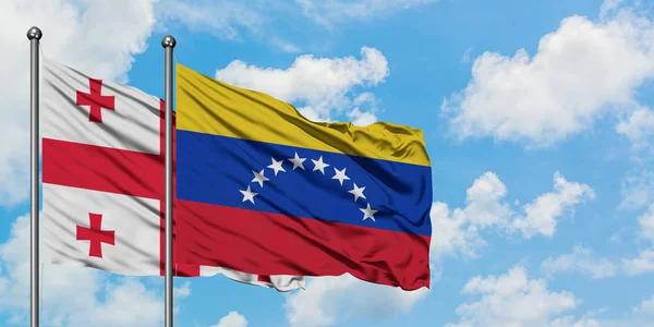 Grúzia és Venezuela zászló integetett a szél ellen, fehér felhős kék ég együtt. Diplomáciai koncepció, nemzetközi kapcsolatok. — Stock Fotó