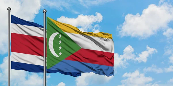 Bandera de Costa Rica y Comoras ondeando en el viento contra el cielo azul nublado blanco juntos. Concepto diplomático, relaciones internacionales . — Foto de Stock
