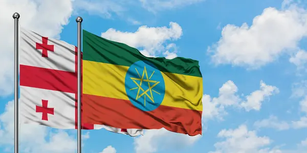 一緒に白い曇り青い空に対して風に手を振るグルジアとエチオピアの旗。外交概念、国際関係. — ストック写真