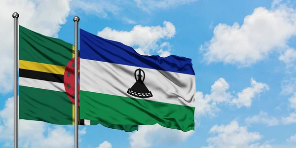 Dominica och Lesotho flagga viftande i vinden mot vit grumlig blå himmel tillsammans. Diplomatisk koncept, internationella relationer. — Stockfoto