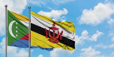 Komorlar ve Brunei bayrağı birlikte beyaz bulutlu mavi gökyüzüne karşı rüzgarda sallayarak. Diplomasi kavramı, uluslararası ilişkiler.