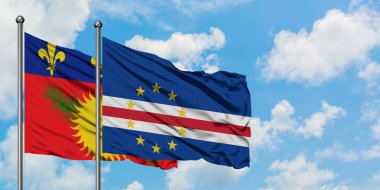 Guadeloupe ve Cape Verde bayrağı birlikte beyaz bulutlu mavi gökyüzüne karşı rüzgarda sallayarak. Diplomasi kavramı, uluslararası ilişkiler.