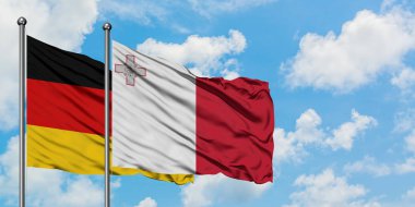 Almanya ve Malta bayrağı birlikte beyaz bulutlu mavi gökyüzüne karşı rüzgarda sallayarak. Diplomasi kavramı, uluslararası ilişkiler.