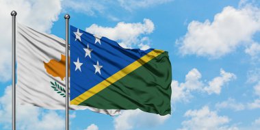 Kıbrıs ve Solomon Adaları bayrağı birlikte beyaz bulutlu mavi gökyüzüne karşı rüzgarda sallayarak. Diplomasi kavramı, uluslararası ilişkiler.