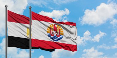 Mısır ve Fransız Polinezyası bayrağı birlikte beyaz bulutlu mavi gökyüzüne karşı rüzgarda sallayarak. Diplomasi kavramı, uluslararası ilişkiler.