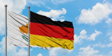 Kıbrıs ve Almanya bayrağı birlikte beyaz bulutlu mavi gökyüzüne karşı rüzgarsal sallayarak. Diplomasi kavramı, uluslararası ilişkiler.