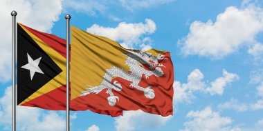 Doğu Timor ve Butan bayrağı birlikte beyaz bulutlu mavi gökyüzüne karşı rüzgarda sallayarak. Diplomasi kavramı, uluslararası ilişkiler.