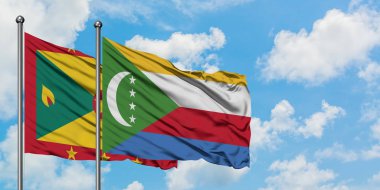 Grenada ve Comoros bayrağı birlikte beyaz bulutlu mavi gökyüzüne karşı rüzgarda sallayarak. Diplomasi kavramı, uluslararası ilişkiler.