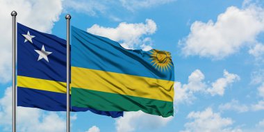 Curacao ve Ruanda bayrağı birlikte beyaz bulutlu mavi gökyüzüne karşı rüzgarda sallayarak. Diplomasi kavramı, uluslararası ilişkiler.