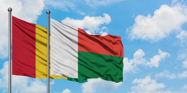 Gine ve Madagaskar bayrağı birlikte beyaz bulutlu mavi gökyüzüne karşı rüzgarda sallayarak. Diplomasi kavramı, uluslararası ilişkiler.