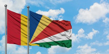 Gine ve Seyşeller bayrağı birlikte beyaz bulutlu mavi gökyüzüne karşı rüzgarda sallayarak. Diplomasi kavramı, uluslararası ilişkiler.