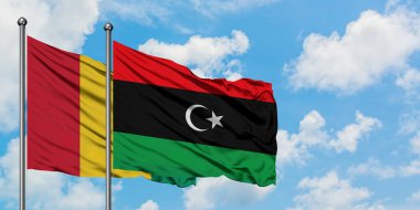 Gine ve Libya bayrağı birlikte beyaz bulutlu mavi gökyüzüne karşı rüzgarsal sallayarak. Diplomasi kavramı, uluslararası ilişkiler.