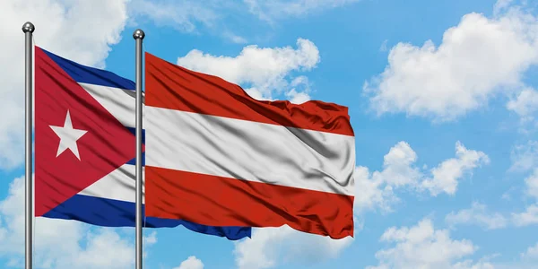 Bandera de Cuba y Austria ondeando en el viento contra el cielo azul nublado blanco juntos. Concepto diplomático, relaciones internacionales . —  Fotos de Stock