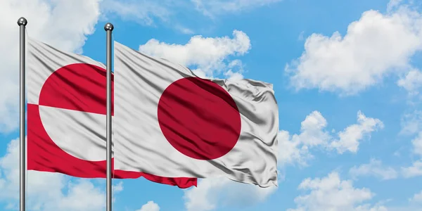 Greenland dan Jepang mengibarkan bendera dalam angin melawan langit biru putih bersama-sama. Konsep diplomasi, hubungan internasional . — Stok Foto