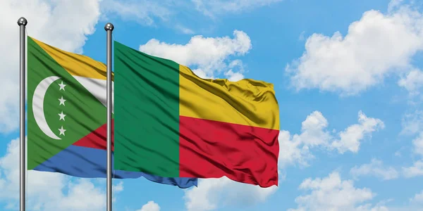 Bandera de las Comoras y Benín ondeando en el viento contra el cielo azul nublado blanco juntos. Concepto diplomático, relaciones internacionales . — Foto de Stock