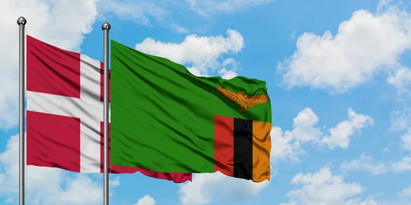 Dánia és Zambia zászló integetett a szél ellen, fehér felhős kék ég együtt. Diplomáciai koncepció, nemzetközi kapcsolatok. — Stock Fotó