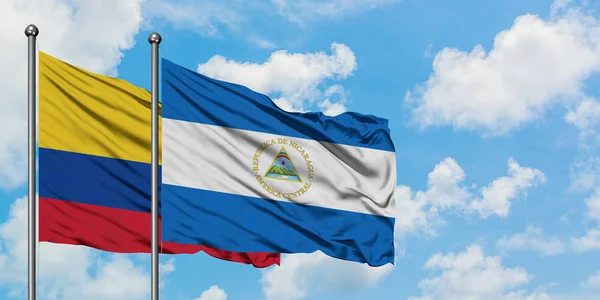 Bandera de Colombia y Nicaragua ondeando en el viento contra el cielo azul nublado blanco juntos. Concepto diplomático, relaciones internacionales . — Foto de Stock